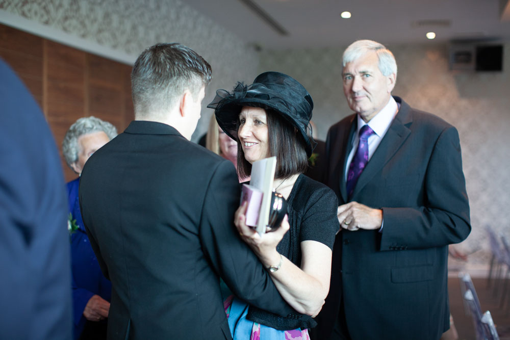 Tim greets his mum warmly, both smiling.