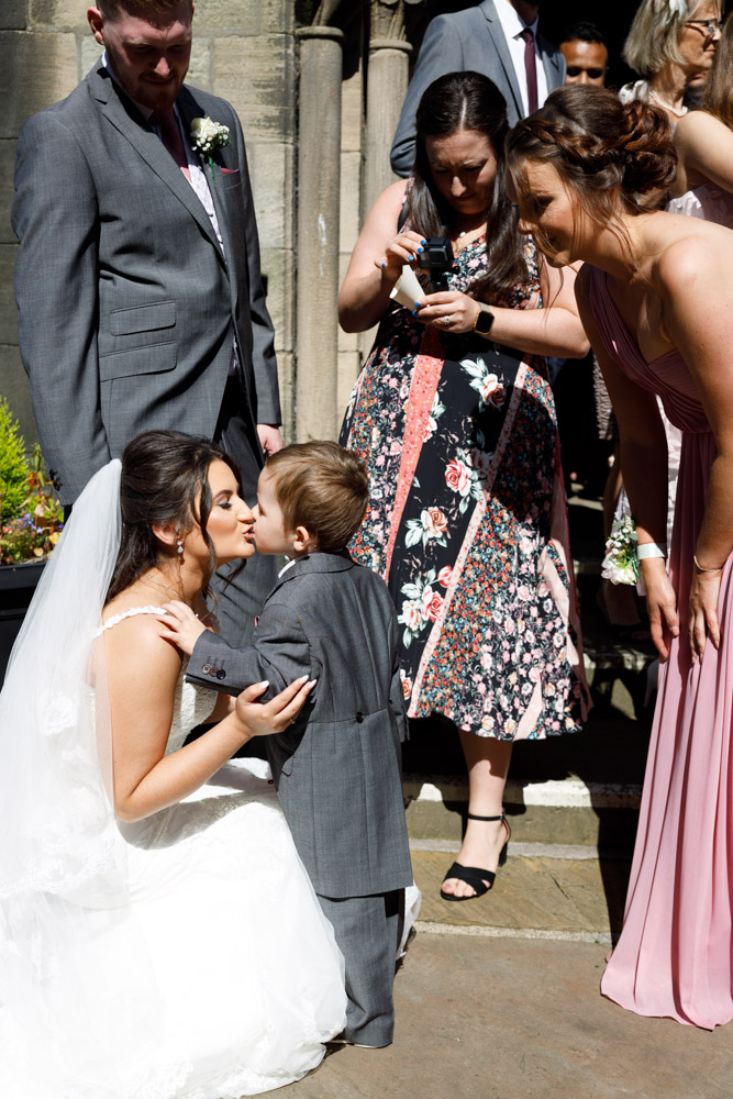 Kyra crouches to kiss her young nephew after the ceremony at St Oswald’s in Guiseley.