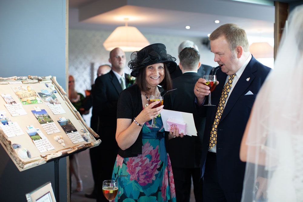 Guests smiling with a wedding photo board in the background.