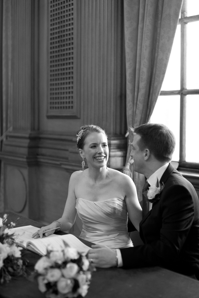 Black and white portrait of the couple seated, turning to look at each other.