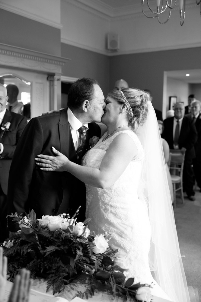 Couple share their first kiss as newlyweds in black and white