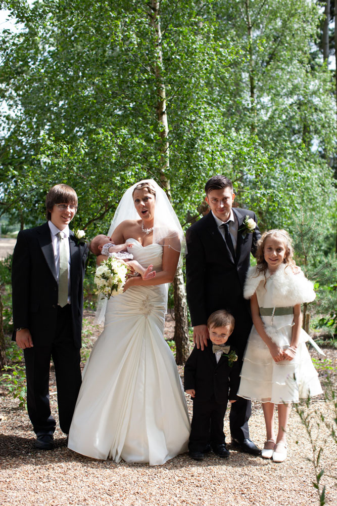 Sam & Tim with four children including a baby in group photo by young trees.