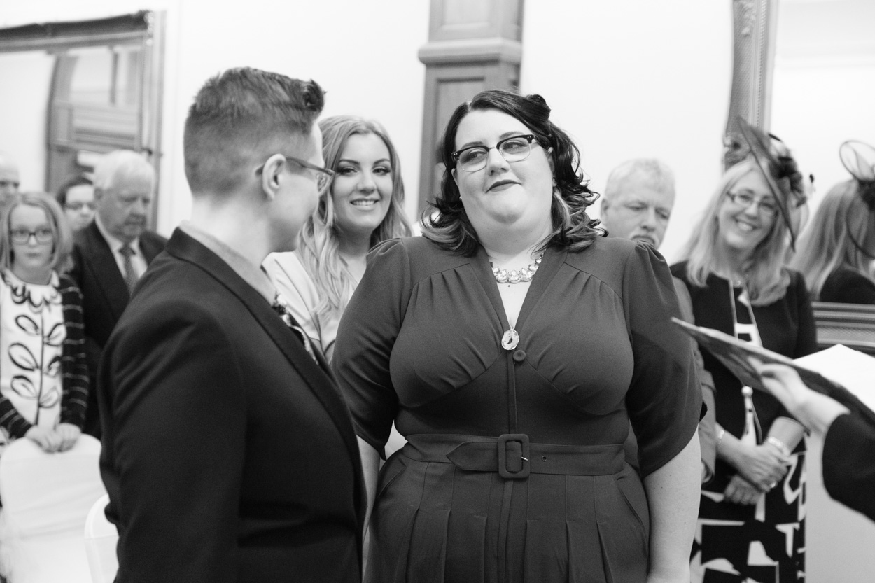 Black and white moment during the vows with sister smiling between them