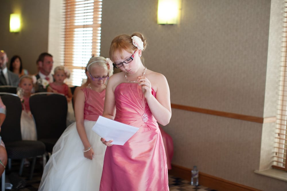 Young daughter looks down, concentrating on her reading at the ceremony.