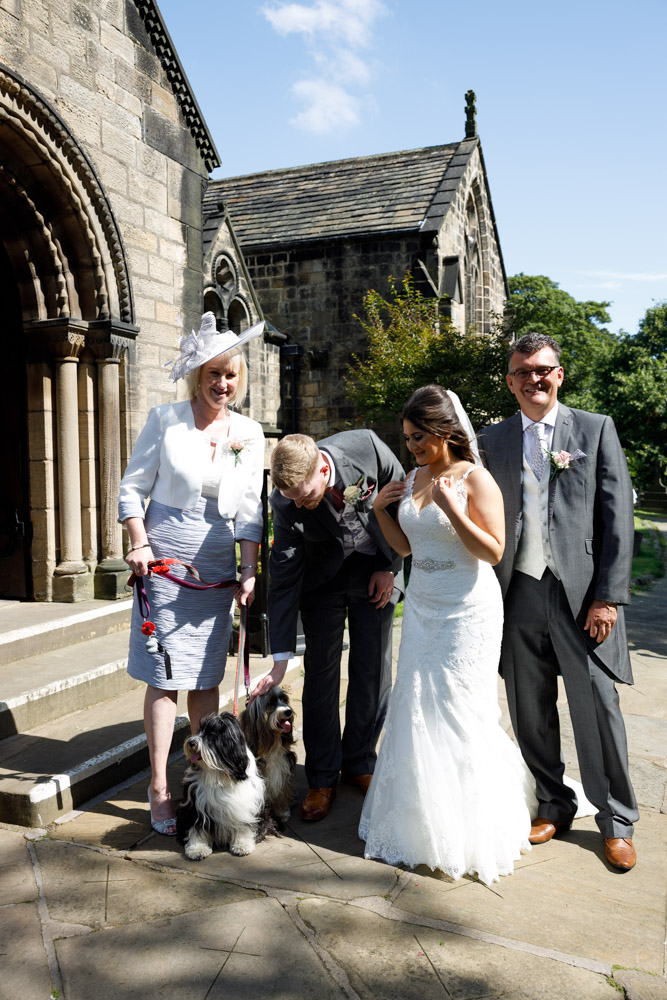 Fun wedding moment with Kyra and her parents as their two dogs join in for the photo outside the church.
