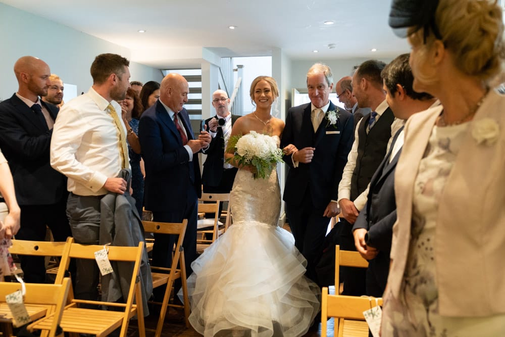 Bride and her father glance towards the groom while walking down the Chilli Barn aisle.