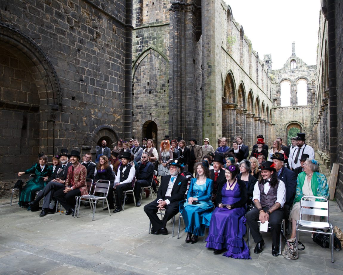 037 guests sat on silver chairs in the spleandour of the abbey church kirkstall abbey wedding linsey and chris