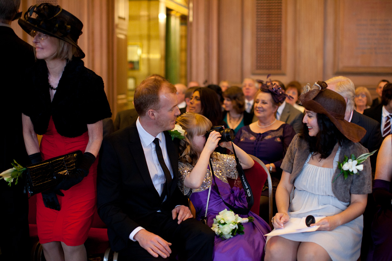 Candid moment as a young bridesmaid photographs her mum on a camera.