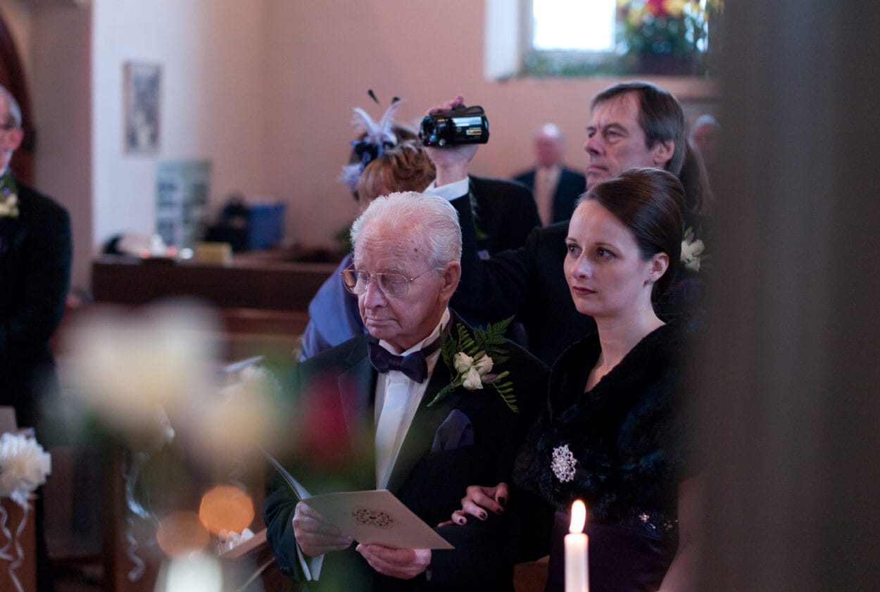 Sister and grandad look toward the couple at the altar.
