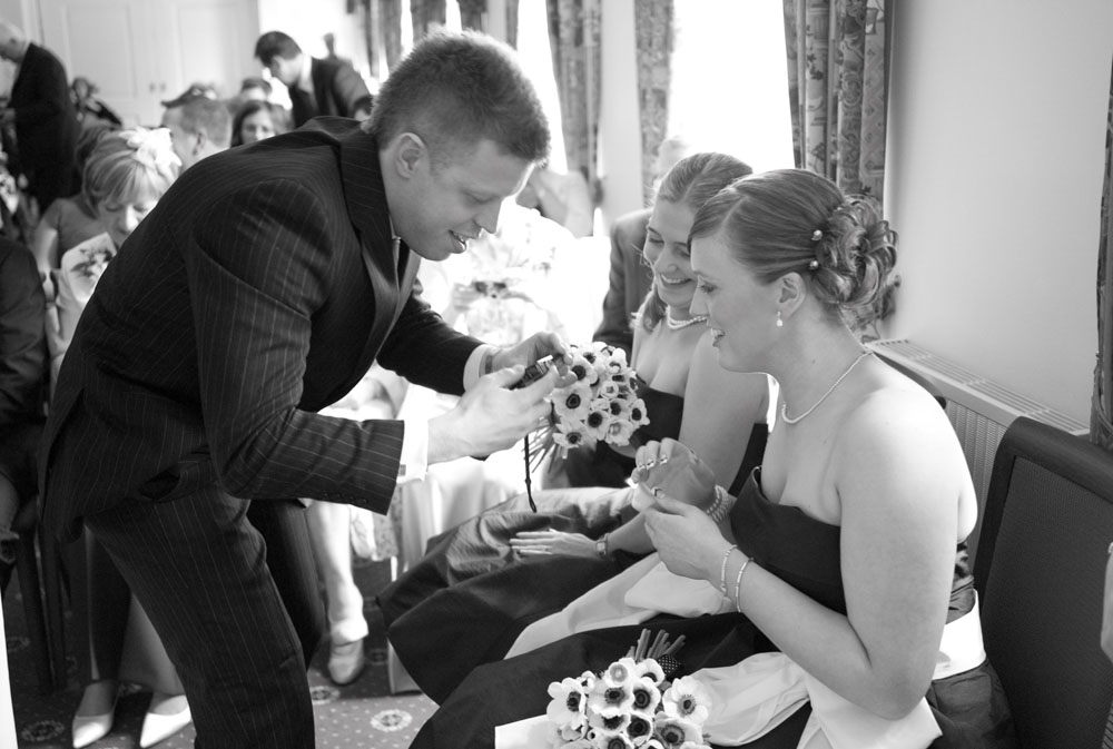 Bridesmaid gives a guest her camera to capture the couple
