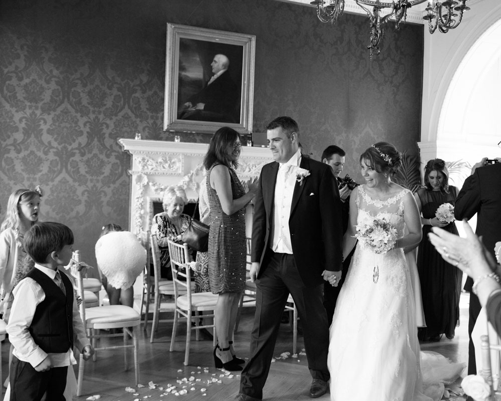 Black and white photo of the couple exiting to applause and smiles from young children.