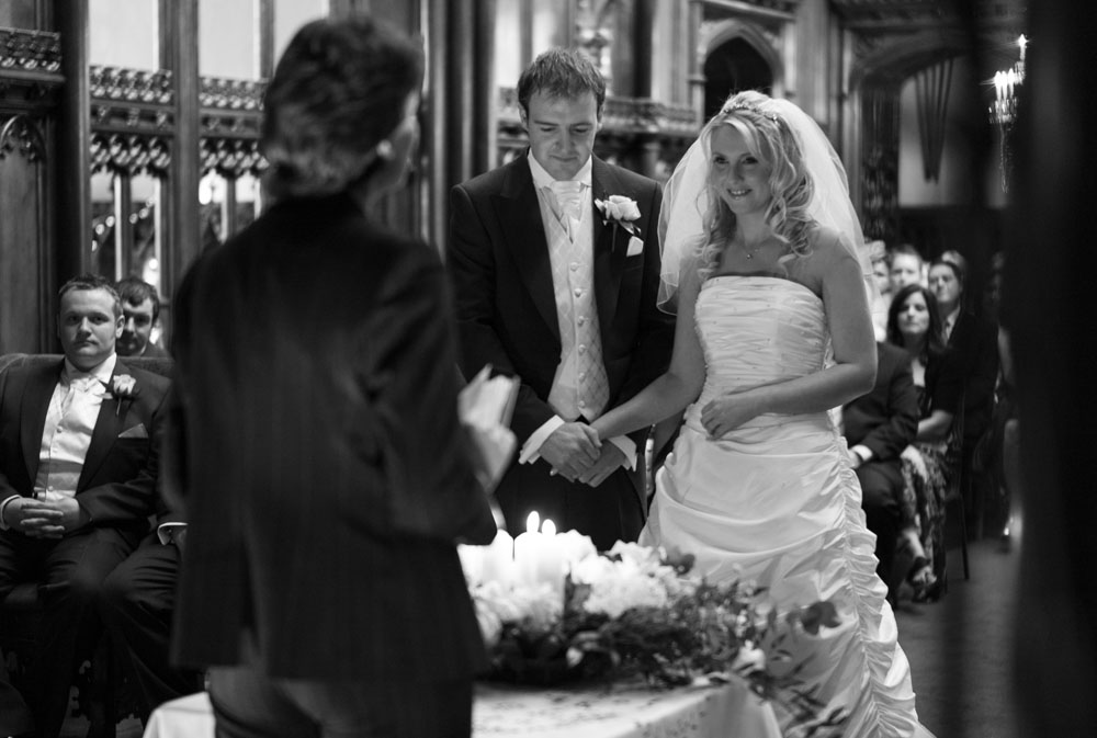 In black and white, the couple hold hands as the registrar begins their wedding ceremony.