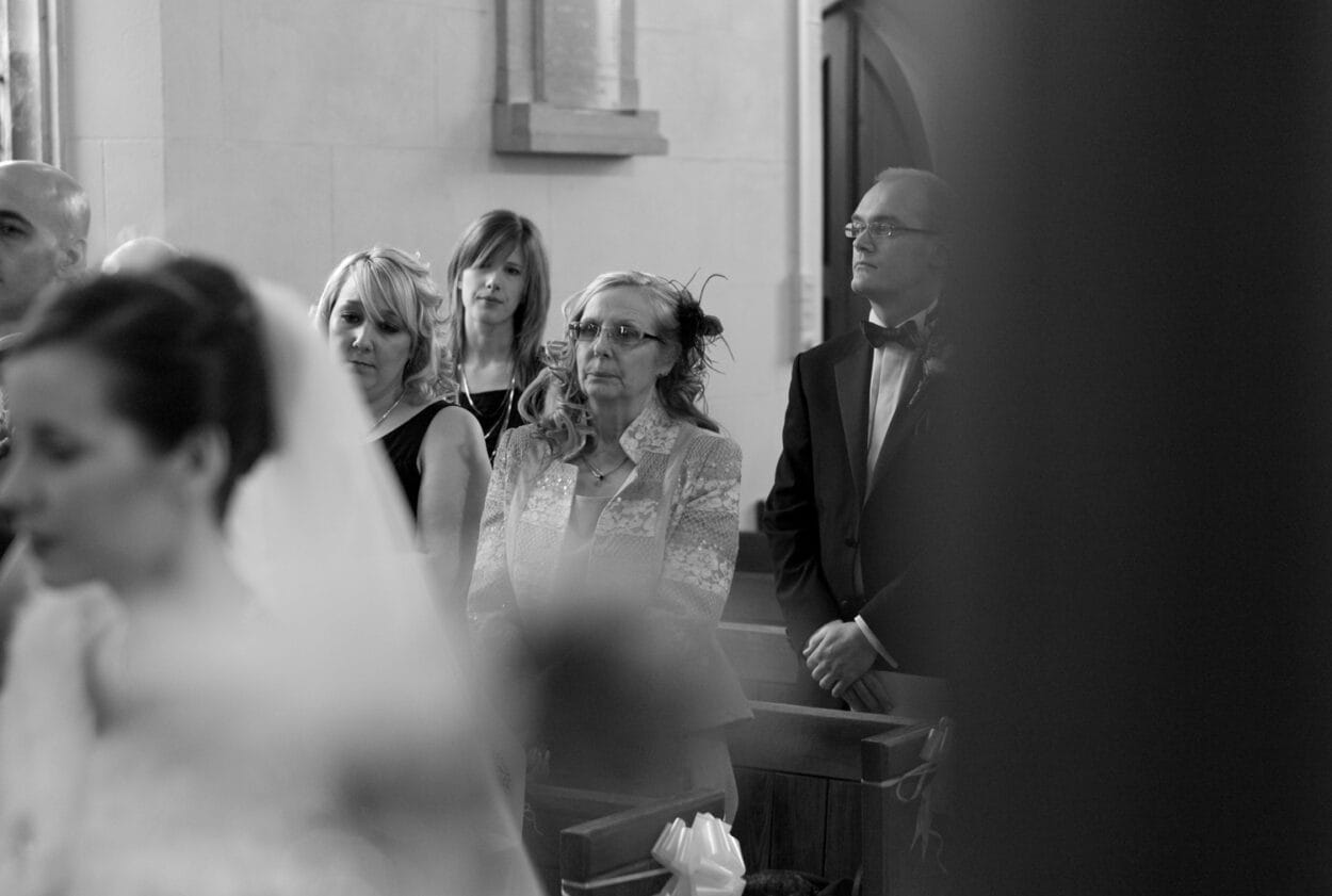 Groom’s mum and sister seated in the church aisle.