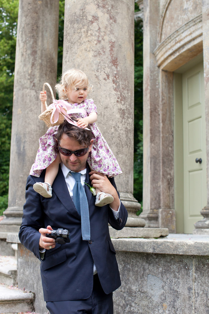 Flower girl sits on her dad’s shoulders in the gardens