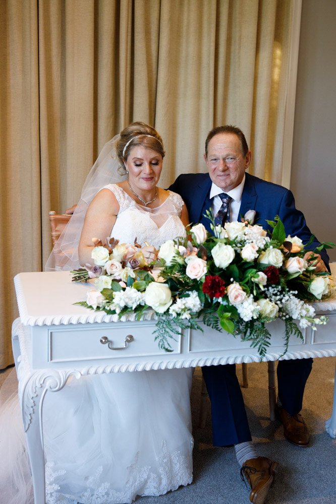 The couple pretend to sign the register for a posed photo