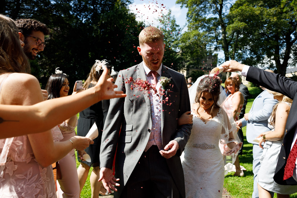 A humorous wedding photo as the couple reacts to the overwhelming confetti moment.