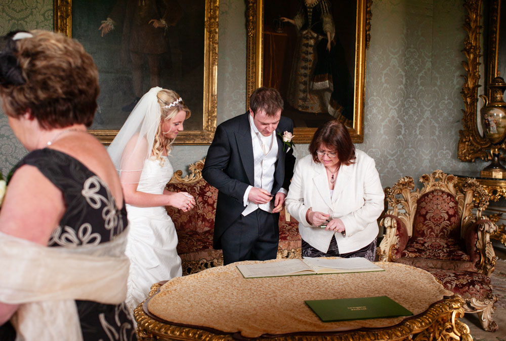 Groom reviews the wedding register in the richly decorated Allerton Castle boardroom.