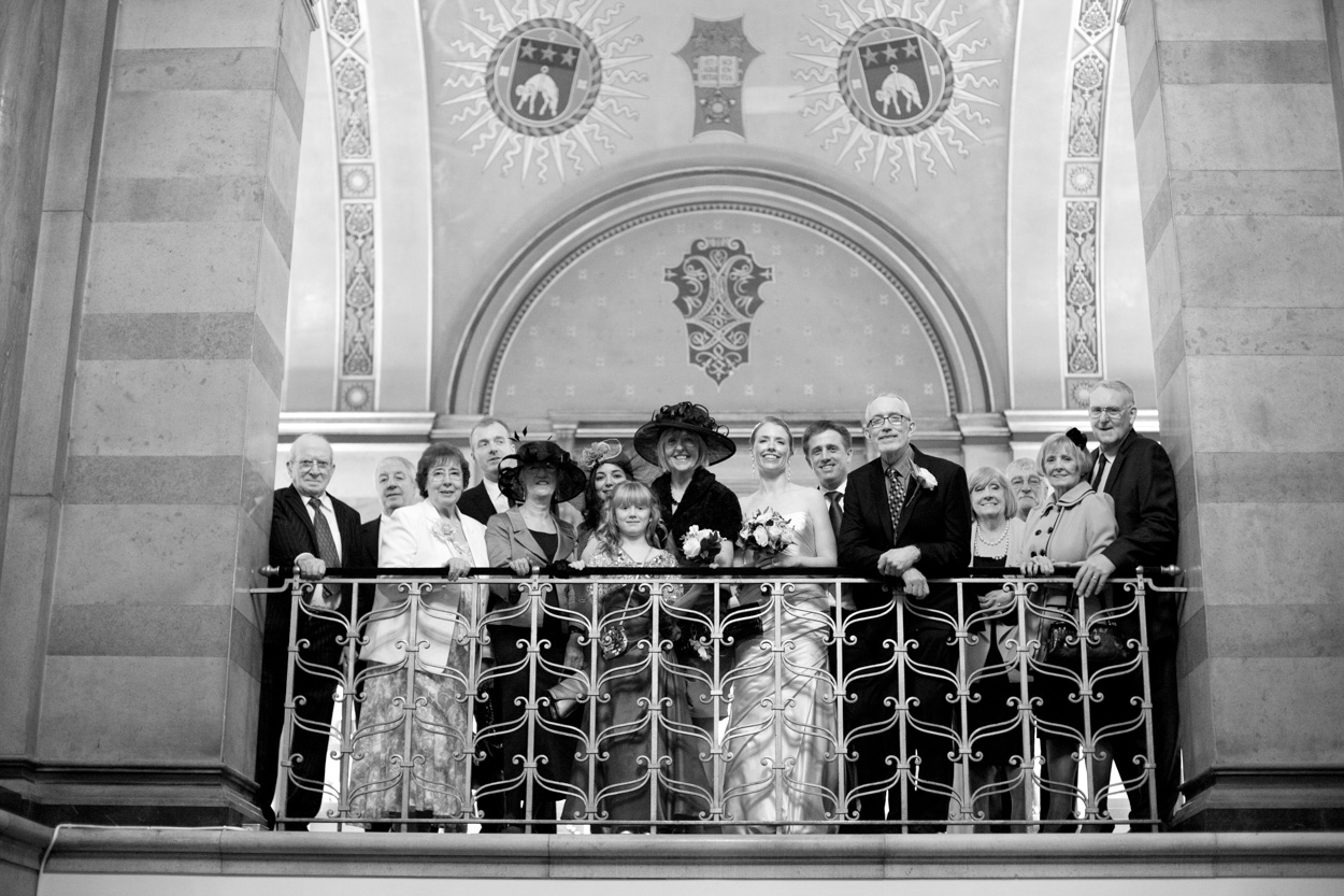 Black and white group portrait on the balcony beneath the ornate ceiling of Leeds Civic Hall.