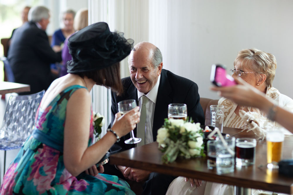 Bride’s father chatting warmly with the groom’s mum indoors.