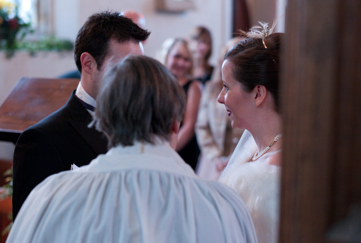 Emelie smiles softly as the vows continue.