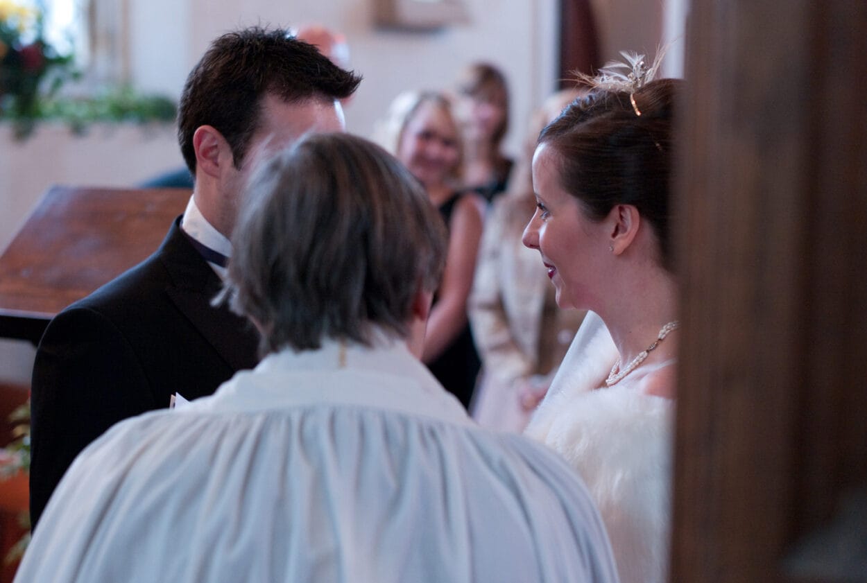 Emelie smiles softly as the vows continue.