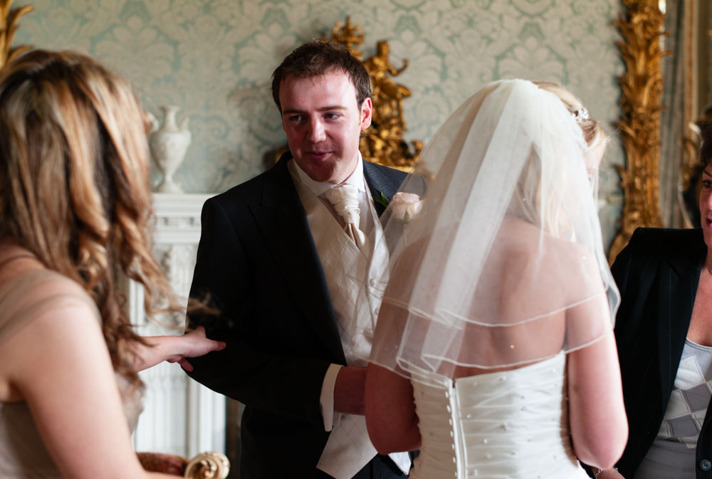 The groom glances back toward the bridesmaids during the register signing.