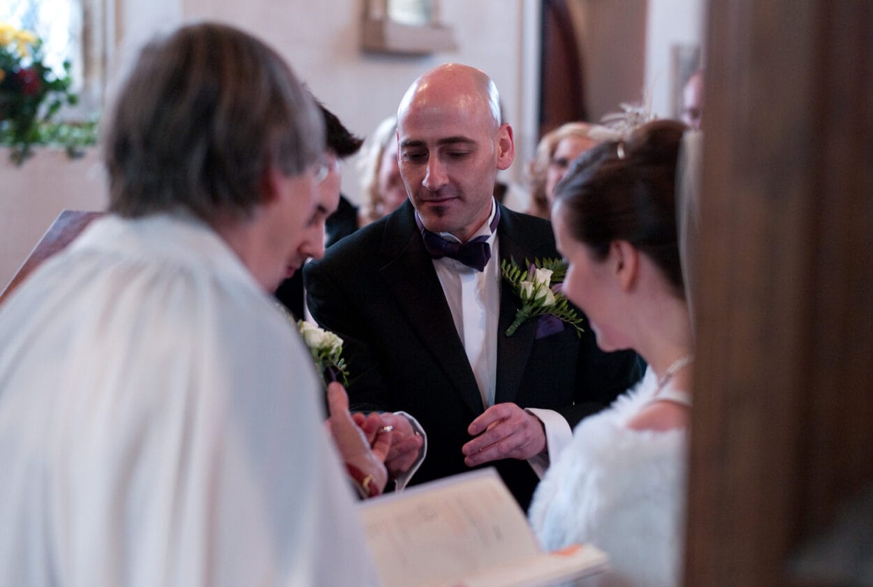 Best man hands the wedding ring to the groom.