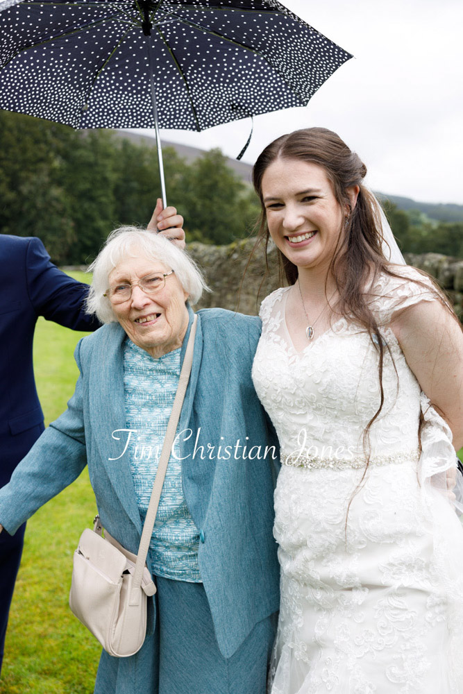 A heartwarming rainy day wedding photo of the bride and her grandmother