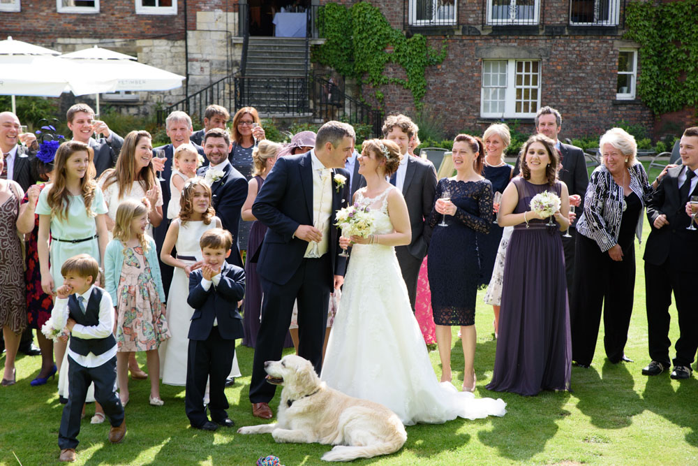 Couple about to kiss, guests smiling around them.