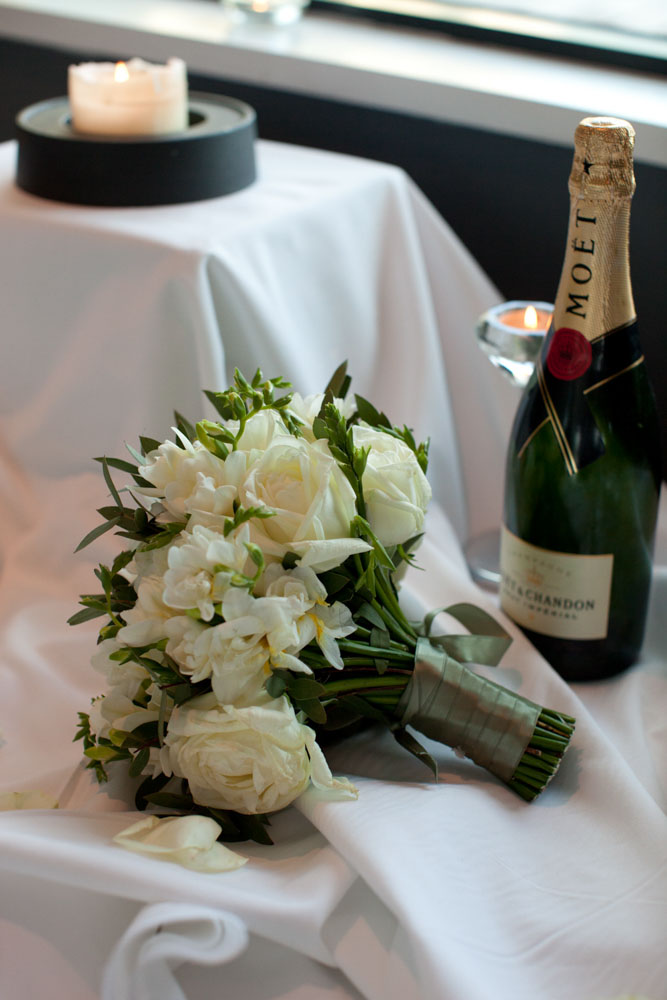 Bride’s bouquet beside a chilled champagne bottle.