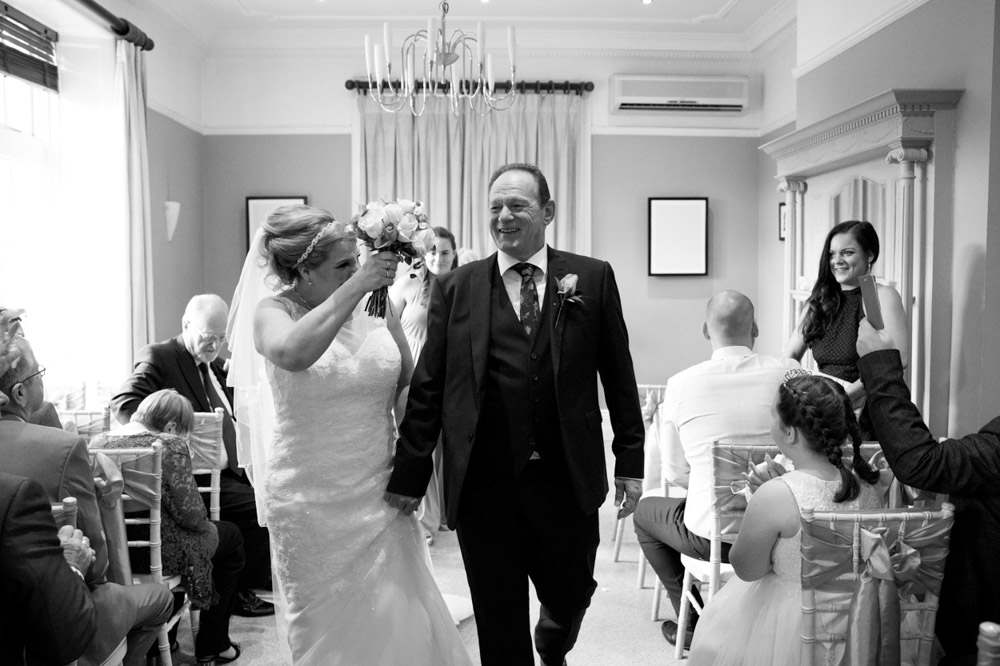 Couple continue down the aisle in black and white