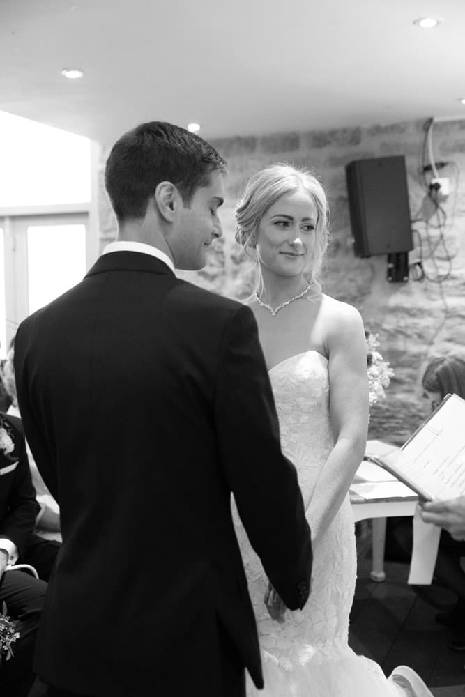 Bride smiles warmly at the registrar while the groom closes his eyes with a soft smile at the Chilli Barn wedding.