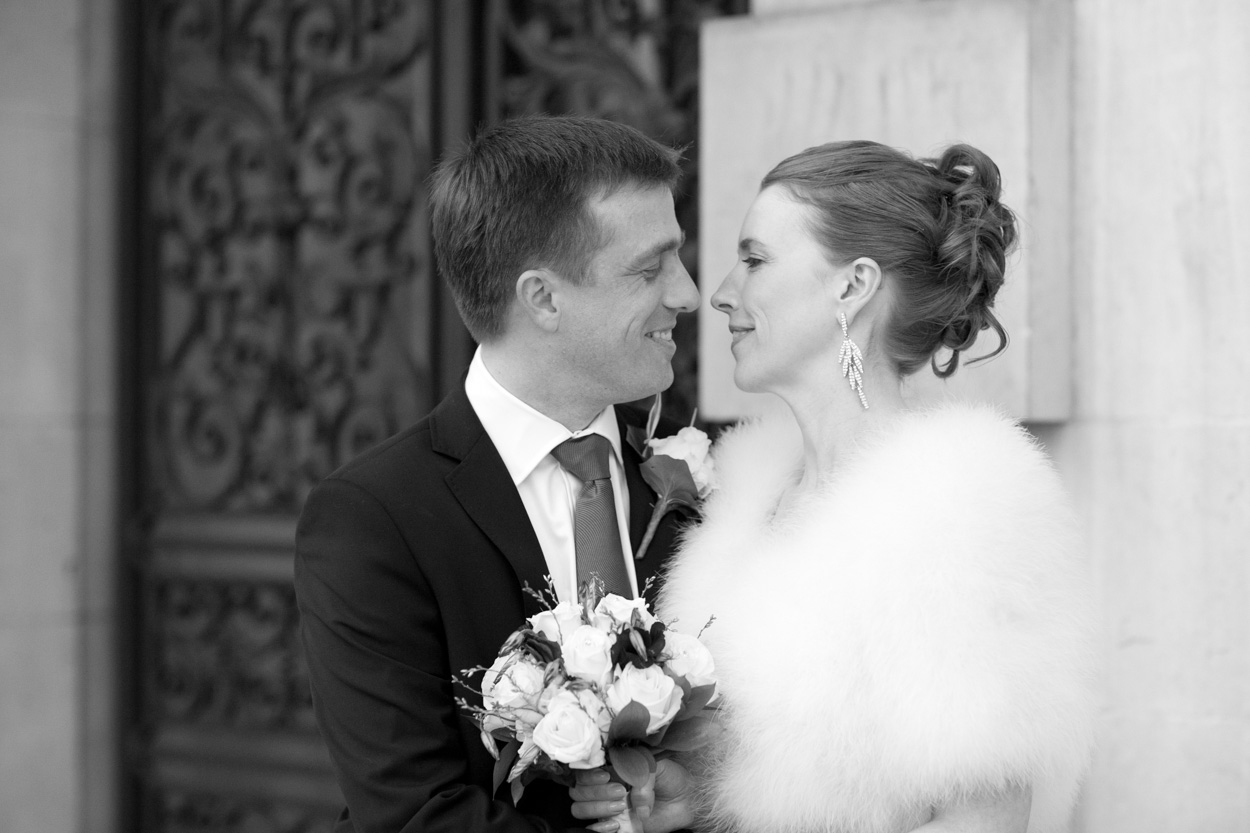 Black and white portrait of the couple smiling at each other outside the Civic Hall.
