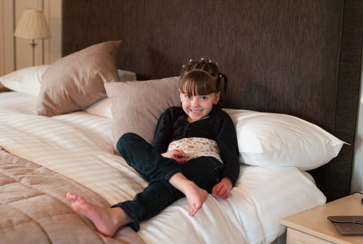 Their daughter smiling on the bed in the bridal suite
