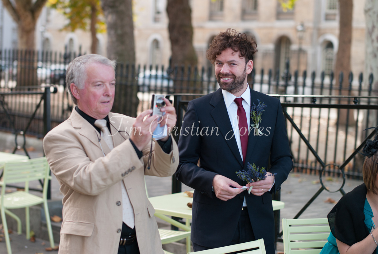 A guest outside in the Trafalgar Tavern courtyard smiling toward the camera as others mingle nearby.