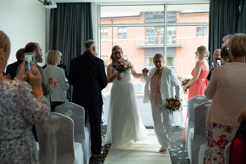Friends and family cheer as the couple dance down the aisle