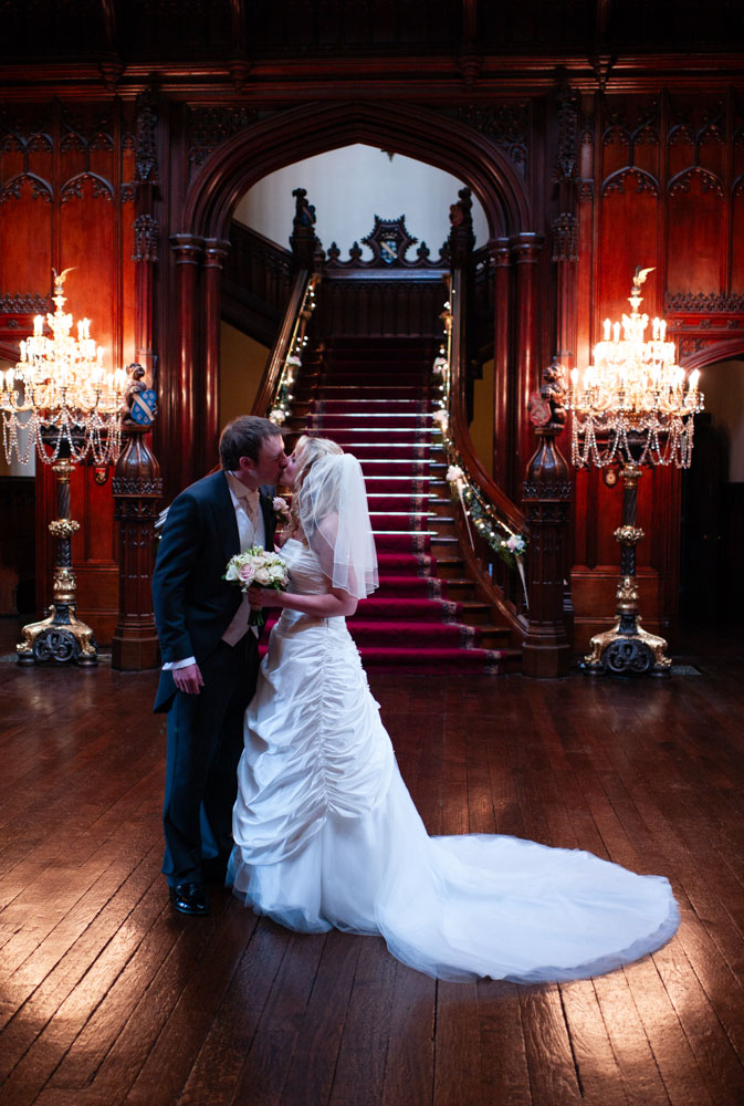 A tender kiss in the warmest golden light inside the grand wedding venue