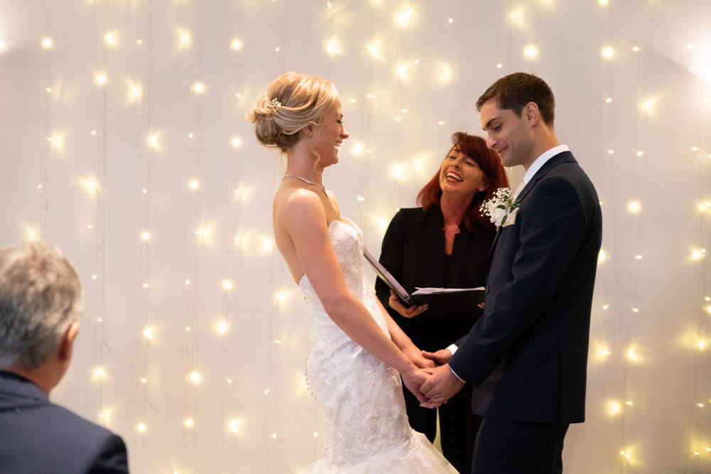 Bride leans back slightly, laughing during her vows at the Chilli Barn, Otley.