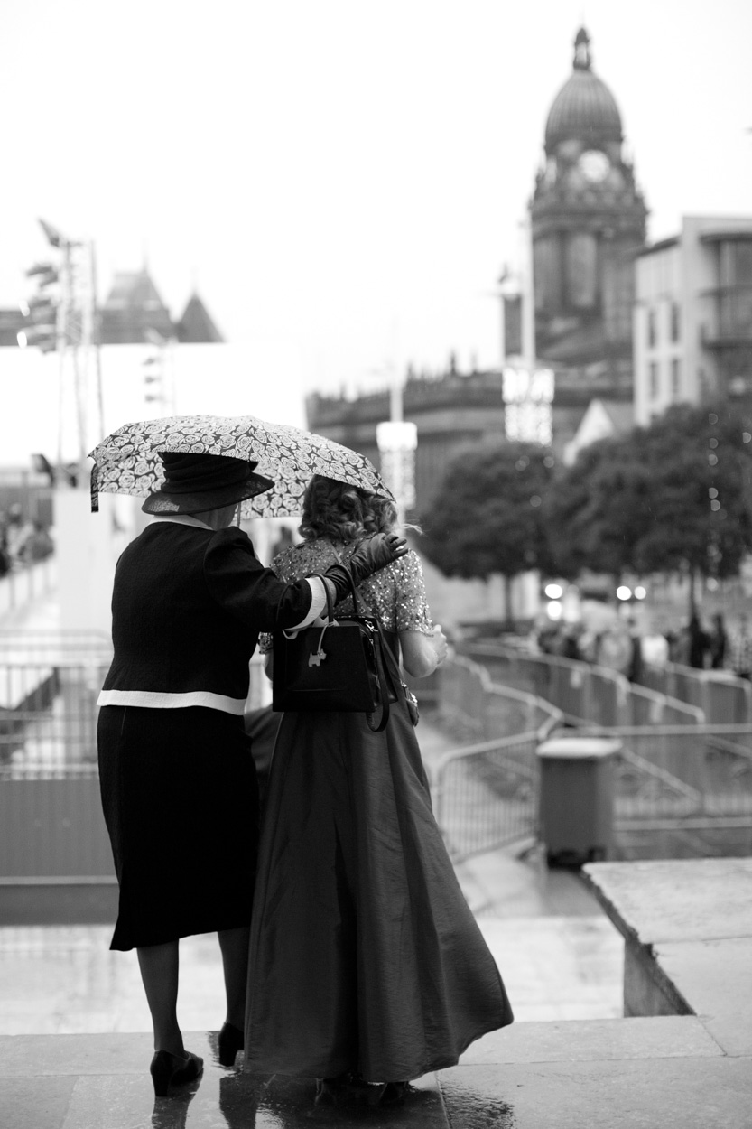 Bridesmaid and grandmother carefully descending the steps under an umbrella.