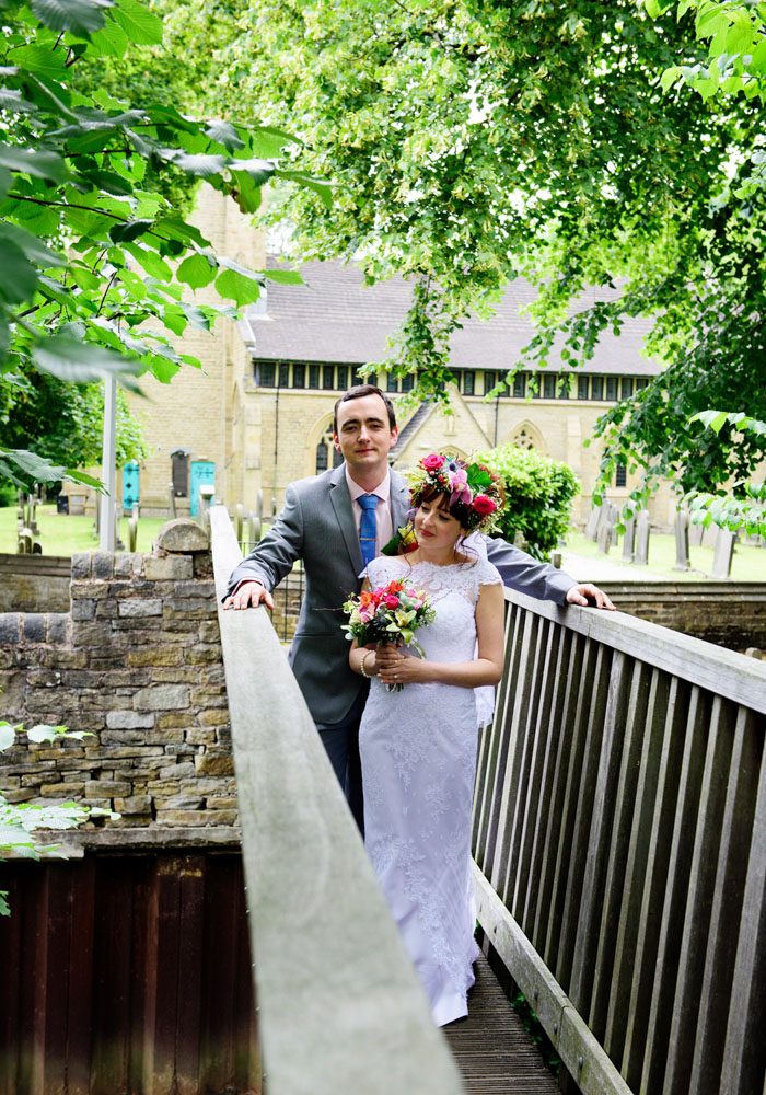 Bride and groom walk across the wooden bridge over the stream at Armitage Bridge.