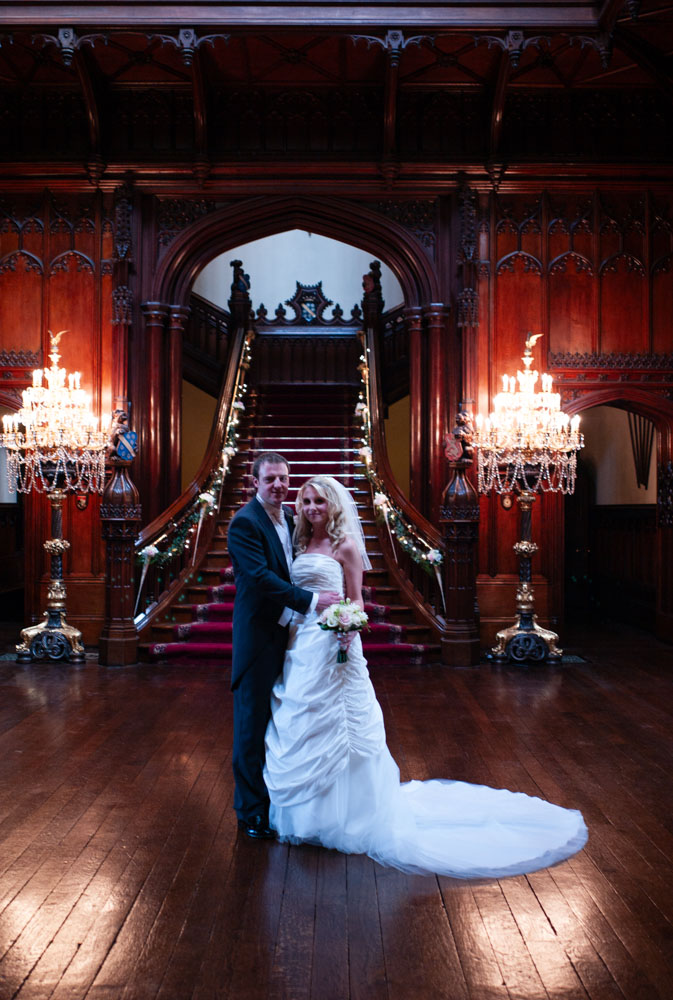 The couple look forward, standing together in soft indoor light