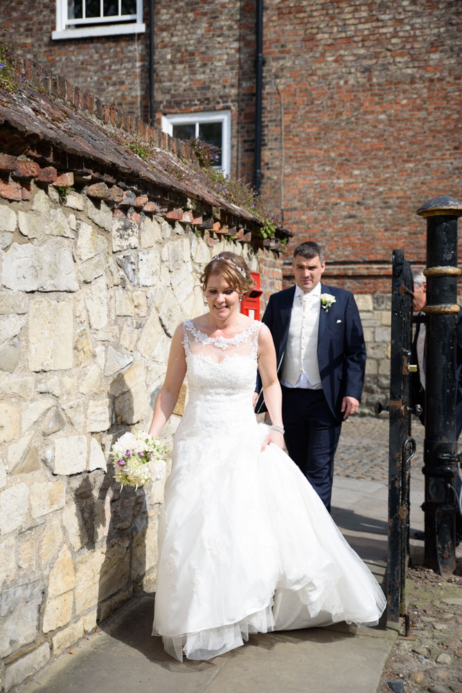 The couple walk down the pathway to the gardens near the minster.