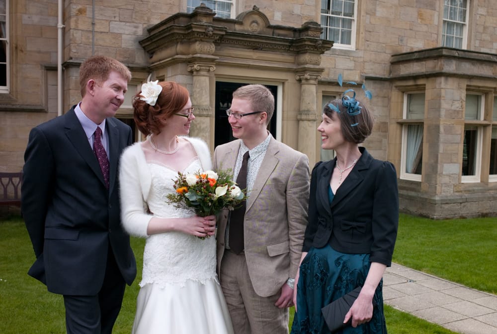 Bride and groom with bride’s parents in relaxed family portrait at Weetwood Hall.