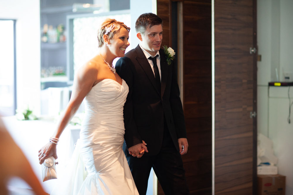 Sam and Tim walk into the wedding breakfast smiling, hand in hand, welcomed by their guests.