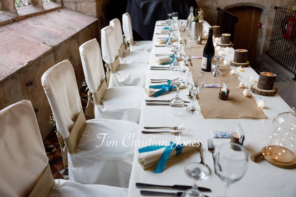 Elegant top table detail with natural wood candles and blue ribbon accents