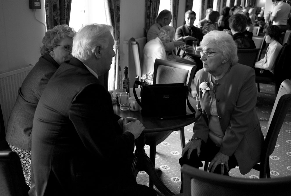 Elderly guests sit together and chat in black and white