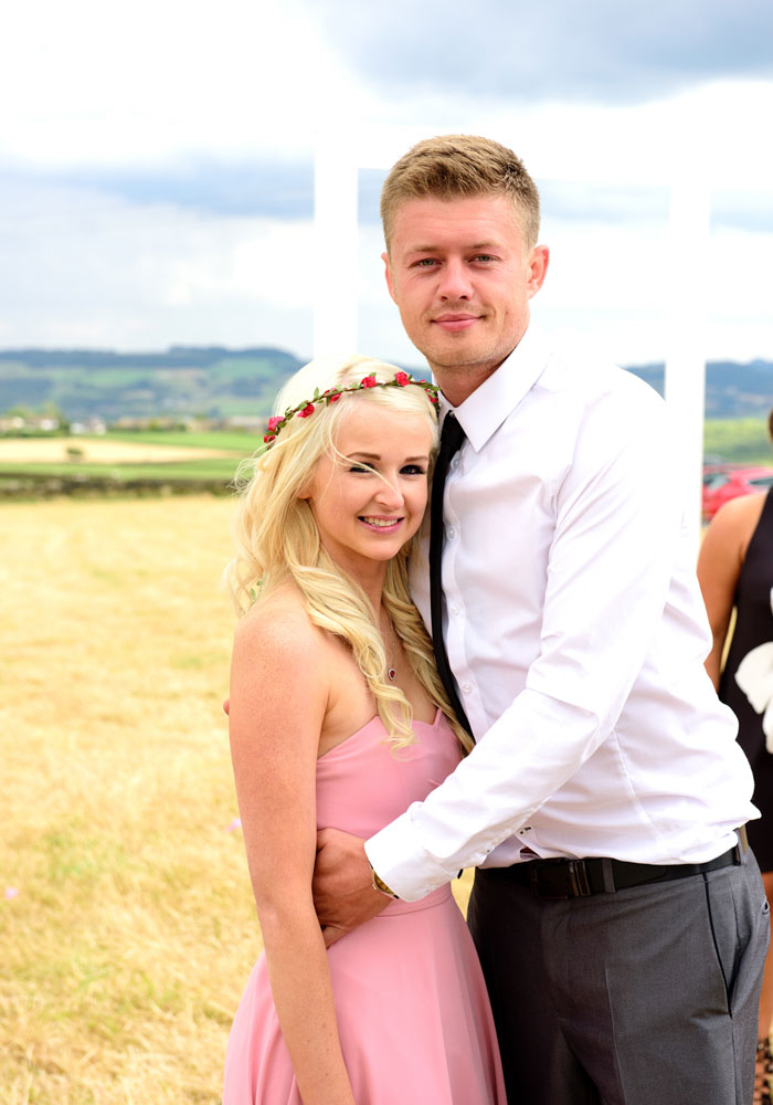 Wedding guests pose together with green West Yorkshire scenery behind them.