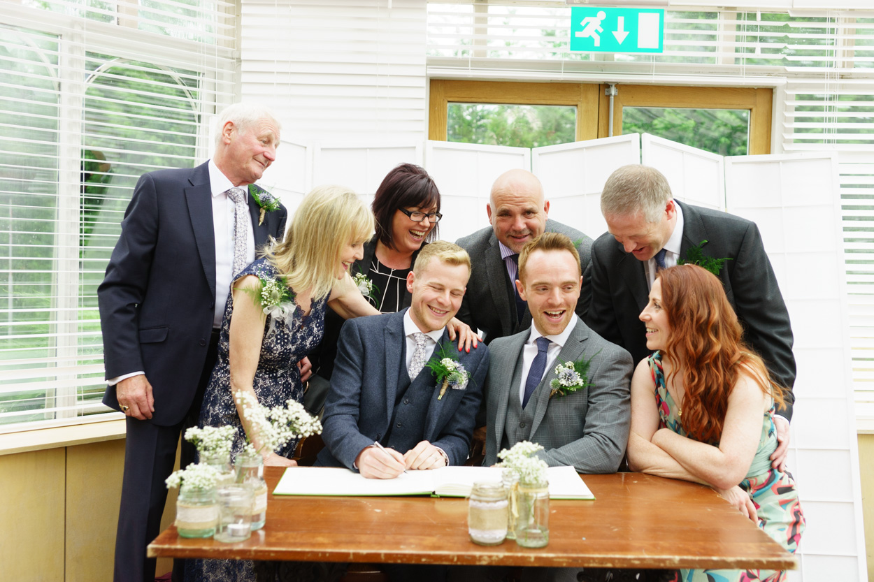 Friends and family gathered around the couple at the signing table