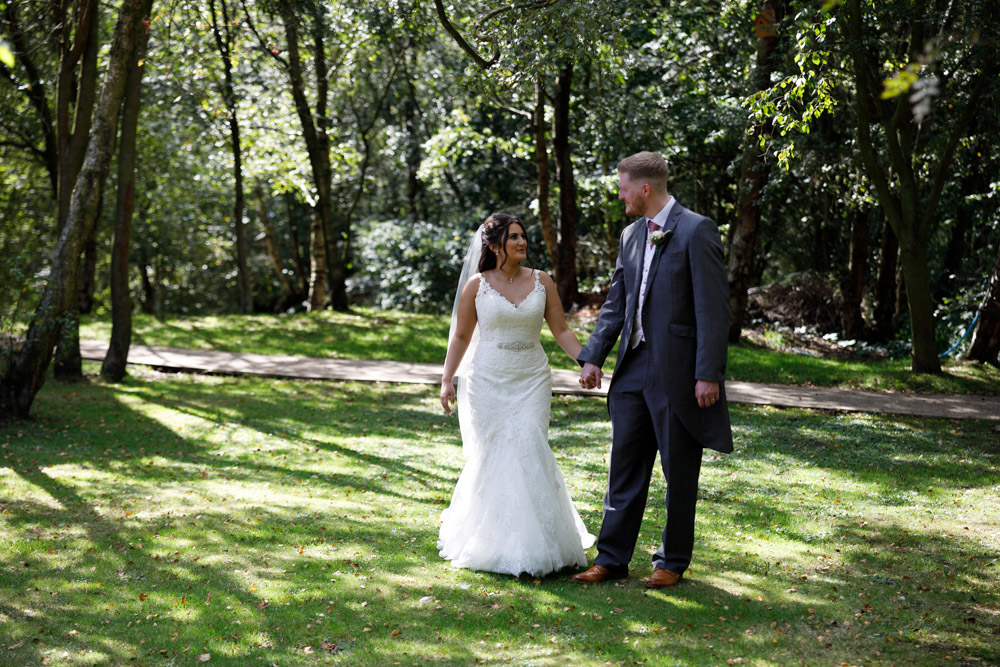 Kyra and Matt walk slowly together through the woodland at Chevin, sunlight dappling around them.