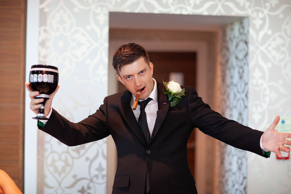 Tim stands posed with his black goblet and a cigar, smiling proudly.